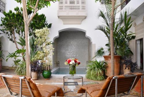 um pátio com um sofá e uma mesa com flores em Riad Al Massarah em Marraquexe
