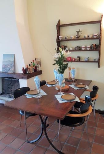 a wooden table with chairs and a table with flowers on it at Vista dolce - Wohnung mit fabelhaftem Blick über die Dächer von Brissago in Brissago