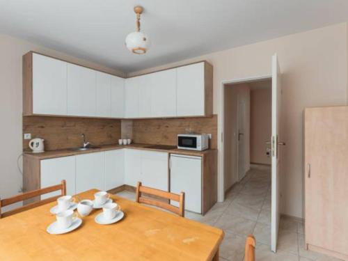 Noclegi Wadowice في فادوفيتسه: مطبخ مع طاولة خشبية ودواليب بيضاء