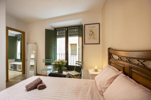 a bedroom with a bed and a chair and a window at Apartament al cor del barri vell de Girona in Girona