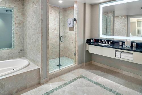 a bathroom with a shower and a tub and a sink at Atlanta Airport Marriott Gateway in Atlanta