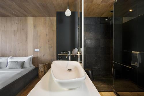a bathroom with a bath tub next to a bed at POD Camps Bay by The Oyster Collection in Cape Town