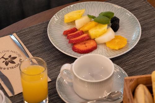 a plate of fruit on a table with a cup of orange juice at AP Dona Aninhas in Viana do Castelo