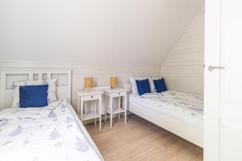 two beds in a room with blue pillows at Apartamenty Tęsknoty 10 in Dziwnów