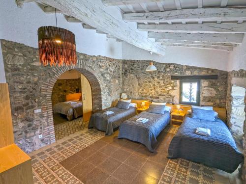 a bedroom with two beds and a stone wall at Masia d'Amer - Complex rural amb encant in Amer