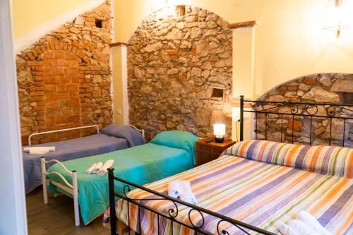 a bedroom with two beds and a stone wall at Affitta Camere Lido&Lida in Campiglia Marittima