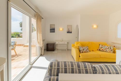 a living room with a yellow couch and a balcony at Villa Cristina in Cala d´Or