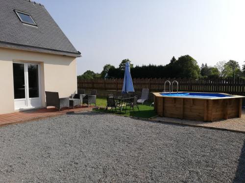 a backyard with a pool and a table and chairs at Agréable maison neuve, 4 personnes, piscine bois privée du 15 juin à mi-septembre in Moëlan-sur-Mer