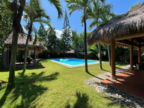 a resort with a swimming pool and palm trees at KUTA - 4BR Villa with Private XL Pool in Kuta