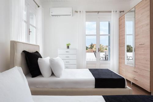 a white bedroom with a bed and a window at Old Port Spetses Mansion in Spetses