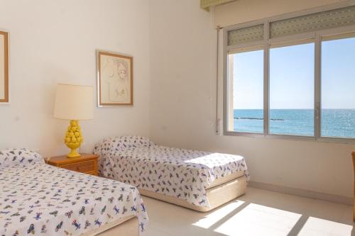 a bedroom with two beds and a window with the ocean at Magnifica VILLA AIREOLA frente al mar in Benicàssim
