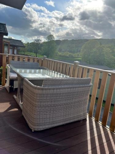 a table and chairs on a deck with a view of the water at Lowena Lodge in Troutbeck