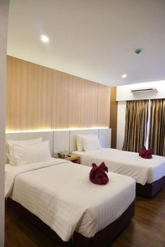 a hotel room with two beds with white sheets at M CASA HOTEL PATTAYA in Nong Prue