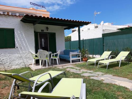 un groupe de chaises et de tables dans une cour dans l'établissement bungalow with private garden, à Playa del Ingles