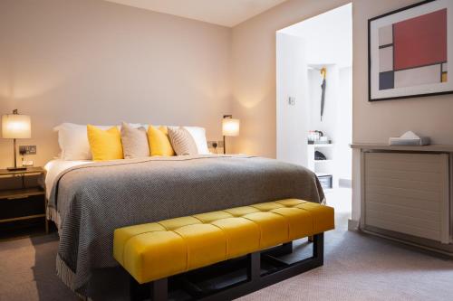 a bedroom with a large bed with a yellow bench at Number 31 in Dublin