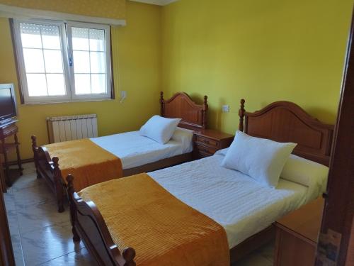 two beds in a room with yellow walls at Casa Fina in Foz
