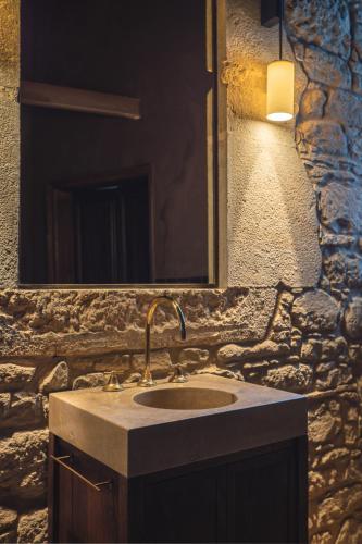 a bathroom sink with a mirror and a stone wall at Can Campolier in Porqueres