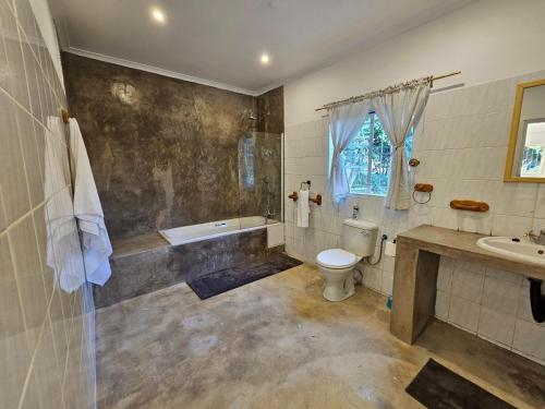 a bathroom with a tub and a toilet and a sink at Thuto Centre Conferencing & Bush Lodge in Bela-Bela