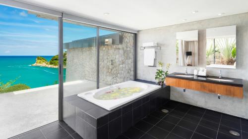a bathroom with a tub and a view of the ocean at Villa Viman in Kathu