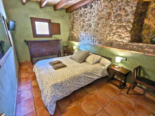 a bedroom with a bed and a stone wall at Can Nofre - Masia familiar en zona tranquila in Amer