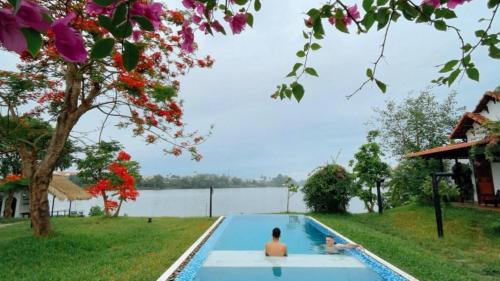 two people sitting in a swimming pool next to a lake at La Y Riverview in Hue