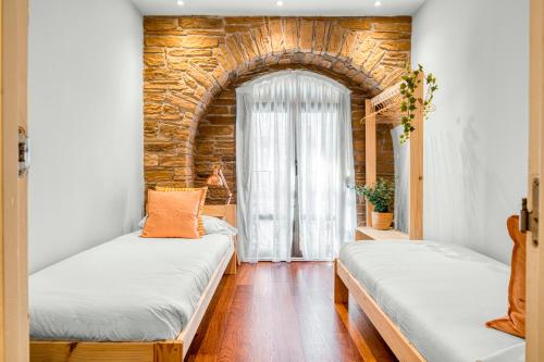 2 camas en una habitación con una pared de ladrillo en Always Easy I Ondarreta en San Sebastián