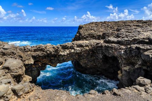 an arch in the rocks next to the ocean at Beautiful Affordable House - 5 minutes from the airport and 12 minutes to Blue bay beach in Mon Trésor