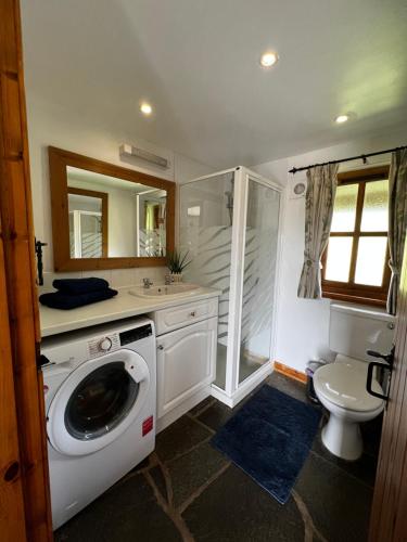 een badkamer met een wasmachine en een toilet bij Tigh Phadraig at Marys Thatched Cottages in Elgol