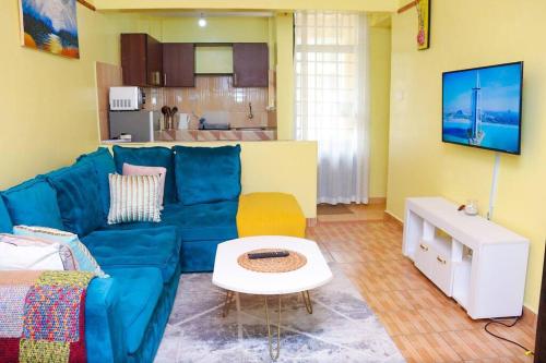 een woonkamer met een blauwe bank en een tafel bij Cosy One bedroom Thika Road,TRM in Nairobi