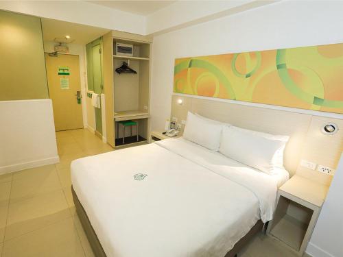 a bedroom with a white bed and a room with a door at Go Hotels Ermita, Manila in Manila