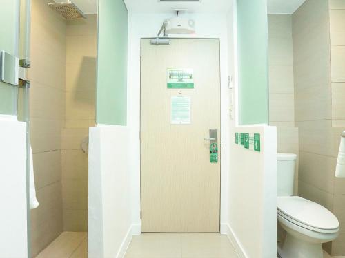 a bathroom with a toilet and a door at Go Hotels Ermita, Manila in Manila