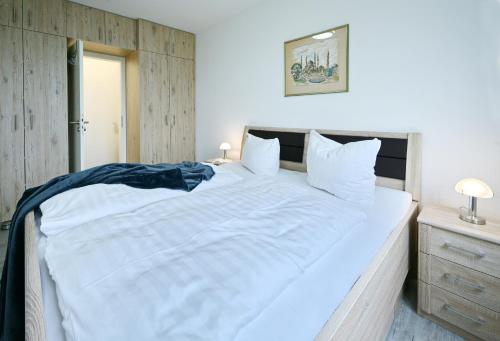 a bedroom with a large white bed with a wooden headboard at Ferienwohnung Hogwarts in Neddesitz