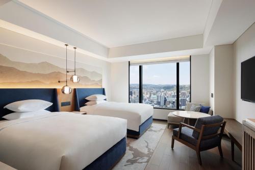 a hotel room with two beds and a window at Sheraton Kagoshima in Kagoshima