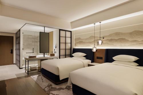 a hotel room with two beds and a desk at Sheraton Kagoshima in Kagoshima
