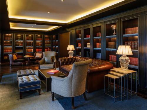 a library with a brown leather couch and chairs at The Europe Hotel & Resort in Killarney