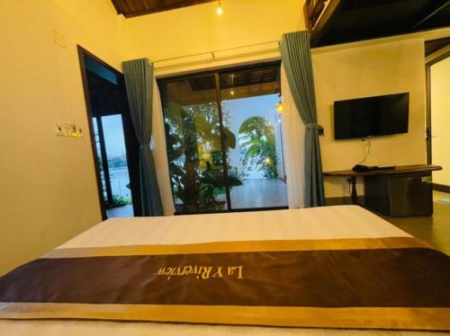 a bedroom with a large bed with a large window at La Y Riverview in Hue
