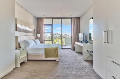 um quarto com uma cama e uma secretária com uma televisão em Lawhill Luxury Apartments - V & A Waterfront na Cidade do Cabo