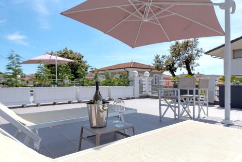 a bottle of wine sitting on a patio with a table and umbrella at Lido Luxury Villas in Lido di Camaiore