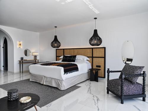 a bedroom with a large bed and a chair at Kouros Hotel & Suites in Mýkonos City