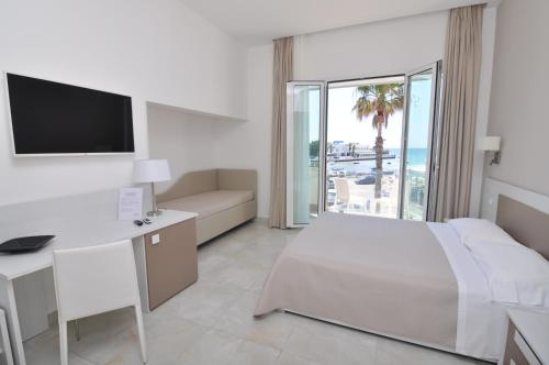 a hotel room with a bed and a desk and a television at Onda B&B in Porto Cesareo