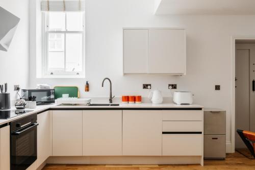 a white kitchen with white cabinets and appliances at Jesticos, Retro Modernised Luxury Very Central Historic Home Free Parking in Canterbury