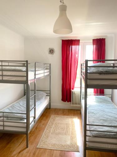 a room with three bunk beds and a window with red curtains at Hässlebogården Turist & Konferens in Mariannelund