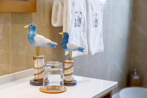 two birds sitting on a counter in a bathroom at Pine Cliff Apartment by The Portuguese Butler in Olhos de Água