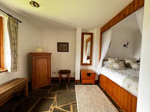 a bedroom with a canopy bed and a mirror at Tigh Phadraig at Marys Thatched Cottages in Elgol