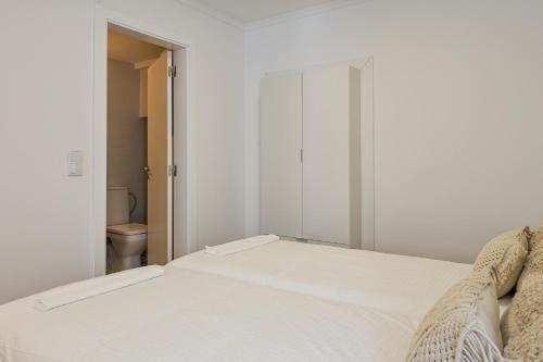 a white bed in a room with a toilet at Chalet Marias - Parede beach apartments in Parede