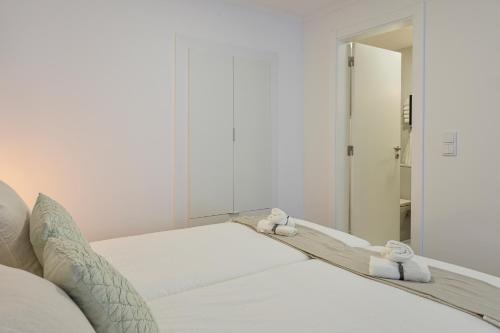 a white bed with two towels on top of it at Chalet Marias - Parede beach apartments in Parede