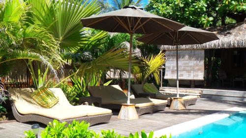 un grupo de sillas y una sombrilla junto a una piscina en Green Lodge Moorea, en Teavaro