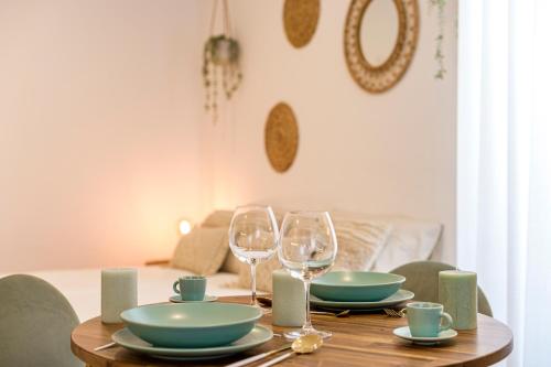 a wooden table with two wine glasses and plates on it at Chalet Marias - Parede beach apartments in Parede