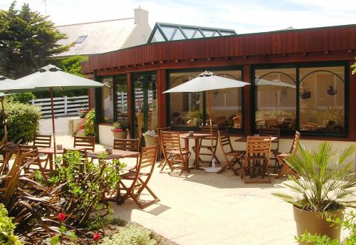 un restaurant avec des tables, des chaises et des parasols dans l'établissement Les Ondines, à Saint-Guénolé