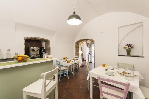 a kitchen and dining room with white tables and chairs at B&B I Tre Camini in Tarquinia